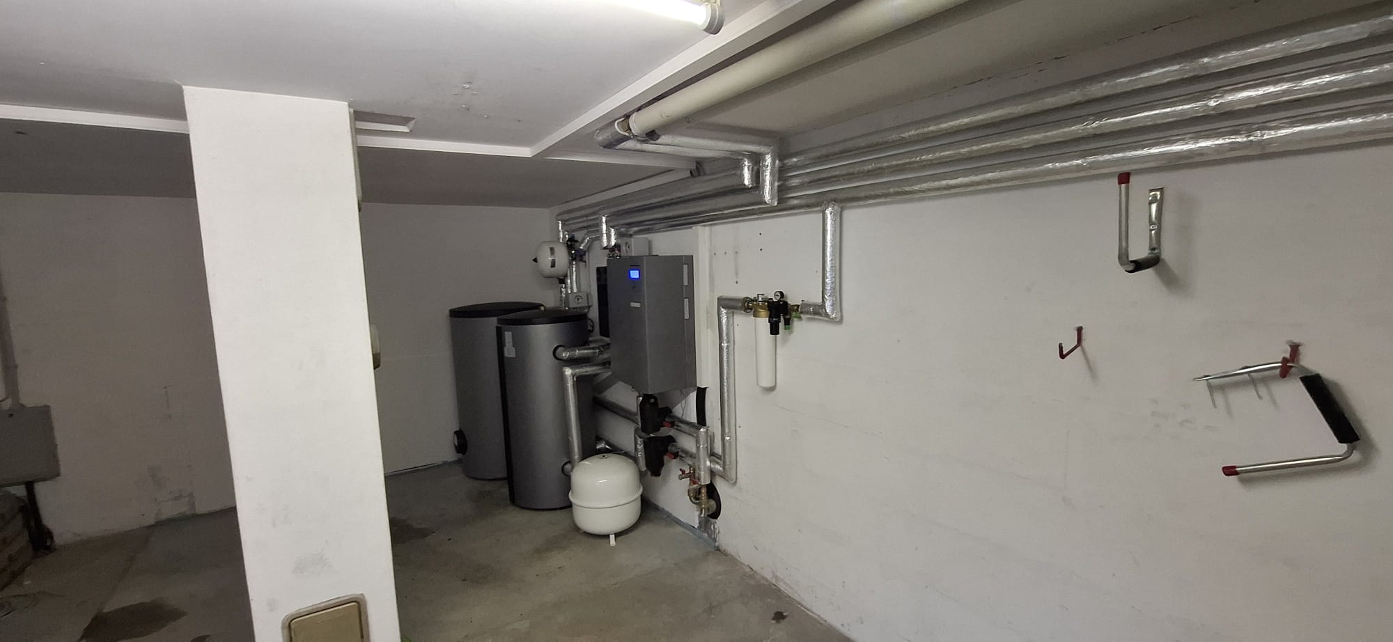 Wärmepumpen-Innenaufbau mit Pufferspeicher, Warmwasserspeicher und Regeltechnik in einem modern ausgestatteten Technikraum.